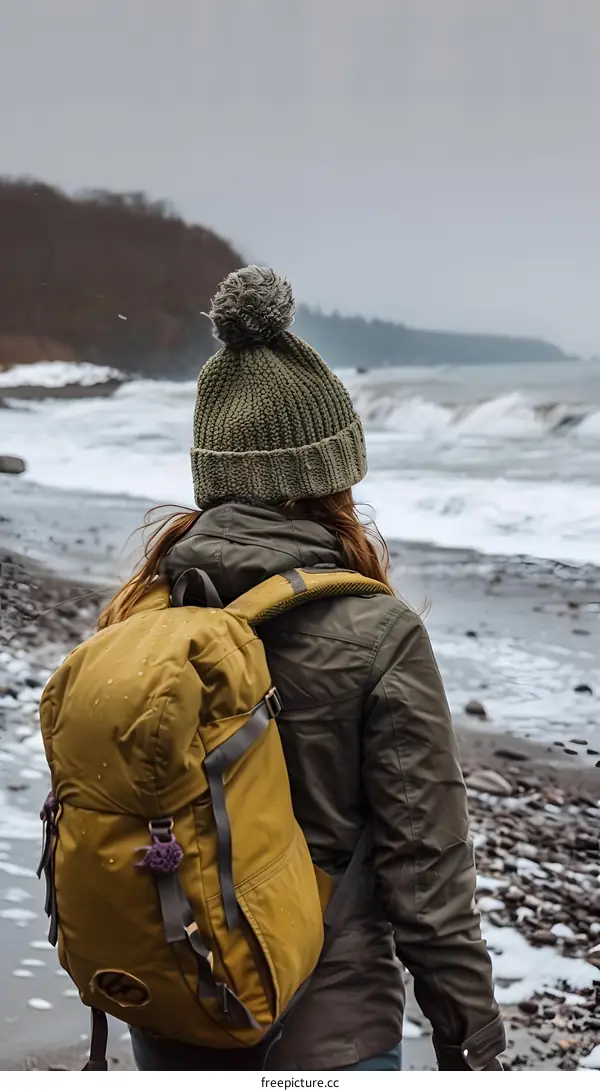 Woman With Backpack Walking On Beach With Ocean Waves Crashing
