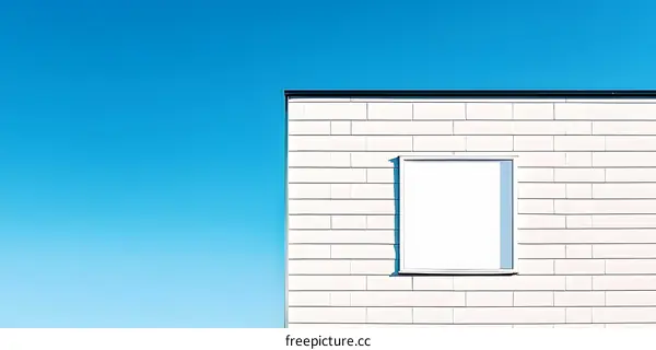 White Brick Wall with a Window Against a Blue Sky