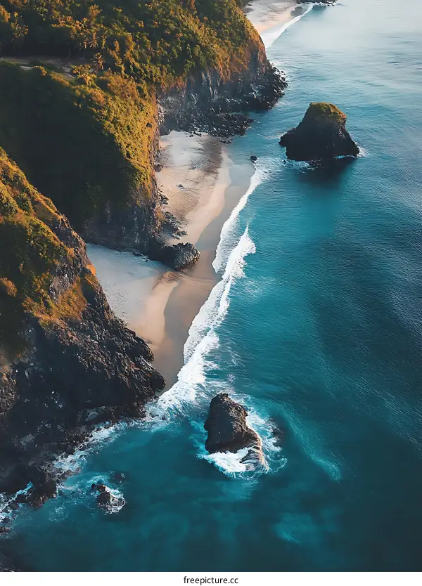 Aerial View of a Sandy Beach with Lush Green Cliffs and Crystal Clear Blue Water