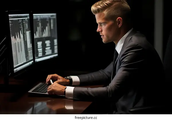 pensive young male professional working on computer in dimly lit office