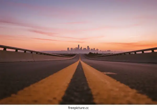 Sunset view of a road leading to a city skyline