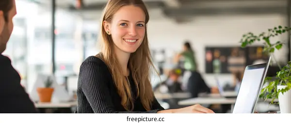 Smiling Woman Working on Laptop in Office Setting