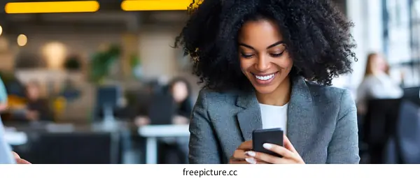 Smiling Black Woman Using Smartphone at Work