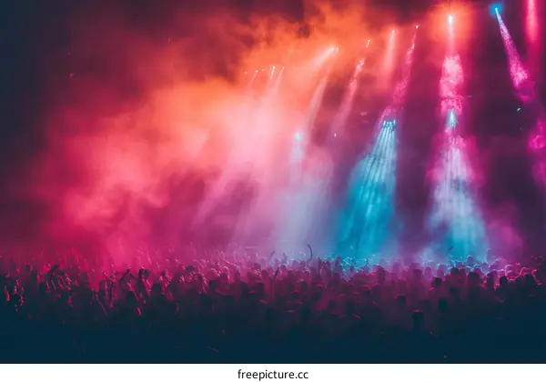 A large crowd of people at a concert with their hands raised in the air