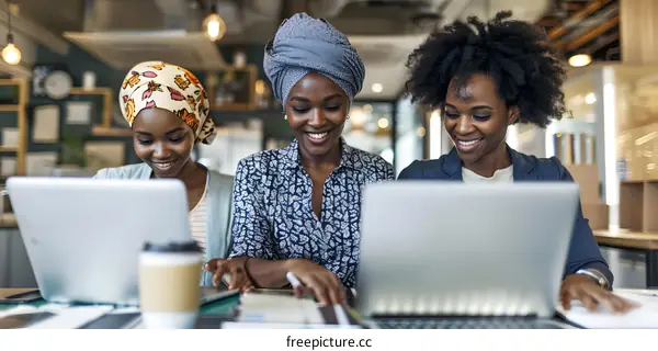 Three African American Women Working Together on Laptops in Office Setting