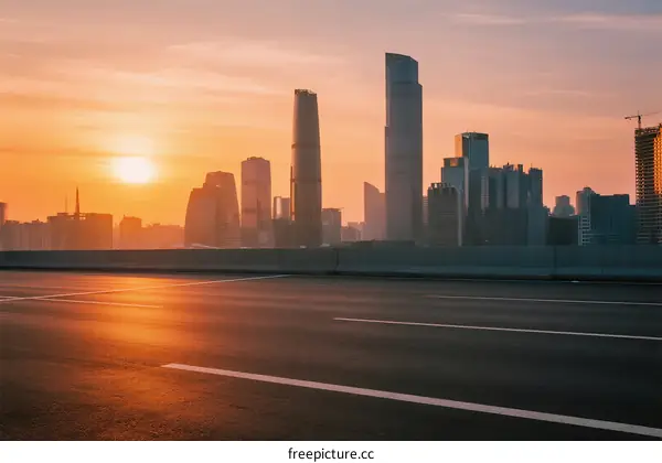 Sunset over modern city skyline with empty road in foreground