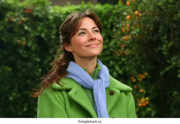 Young woman in green coat looking up outdoors