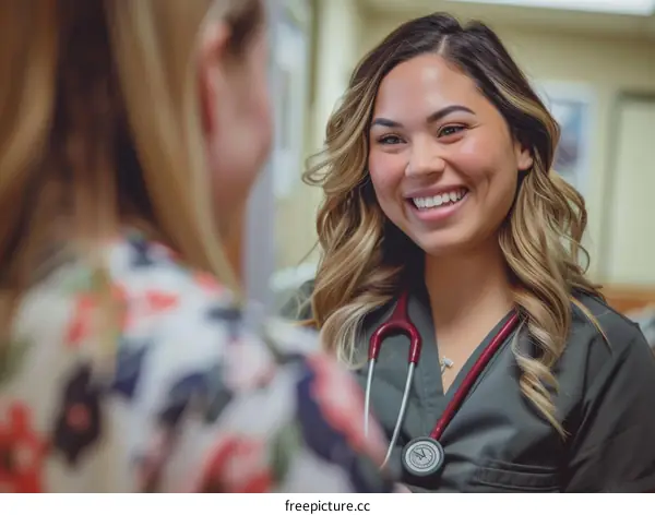 A smiling nurse wearing a stethoscope talks with a patient.