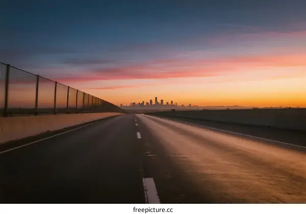 Sunrise over an empty road leading to a city skyline