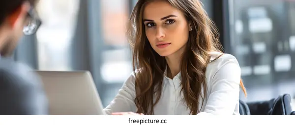 Young Woman Working on Laptop with Serious Expression