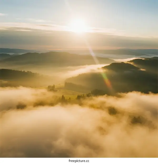 Sunrise over misty mountain range with rolling clouds and golden light