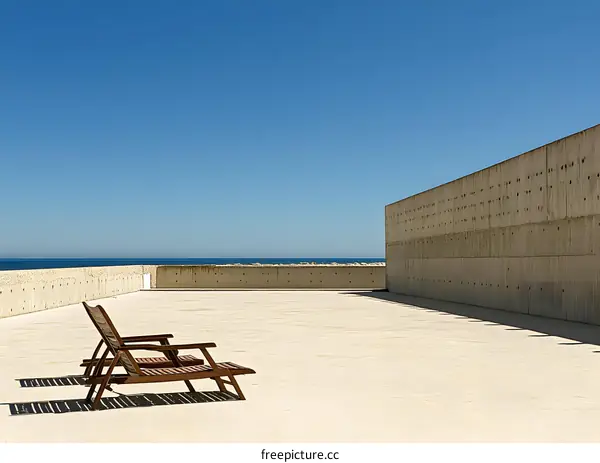 Minimalist Concrete Architecture with Two Wooden Chairs Facing the Ocean