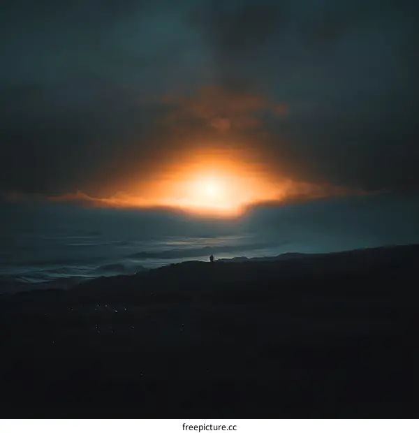 Silhouette of a Person Standing on a Cliff Overlooking the Ocean During Sunset