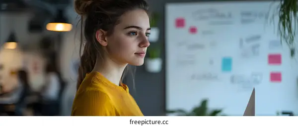 Young Woman in Yellow Sweater Looking at Whiteboard in Office