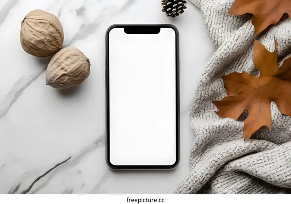 White Marble Surface With Smartphone, Nuts, Pine Cone and Autumn Leaves