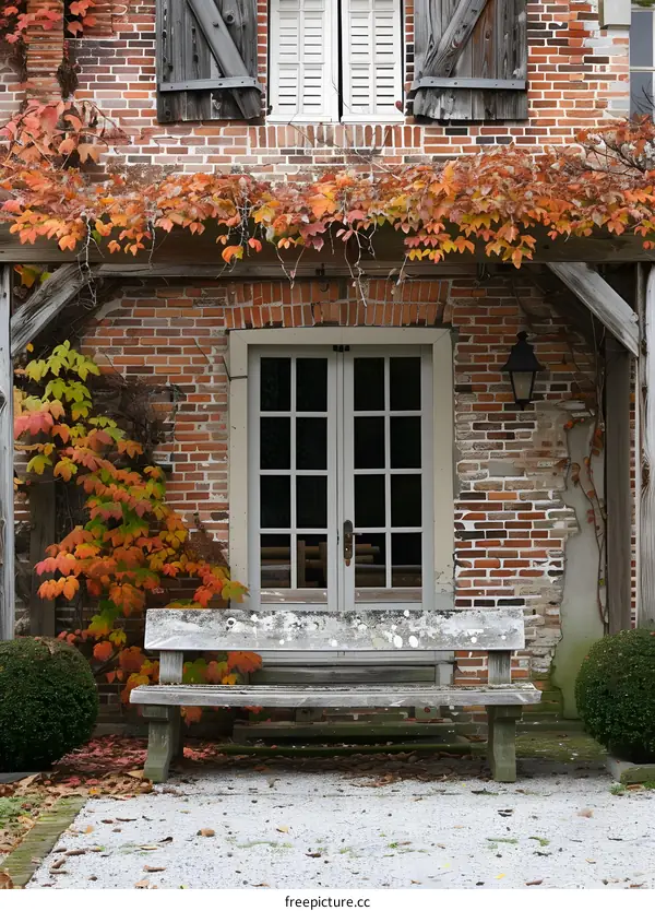 An old bench sits in front of a brick house.