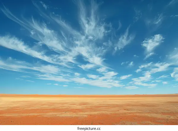 Vast Desert Landscape Under a Blue Sky with White Clouds