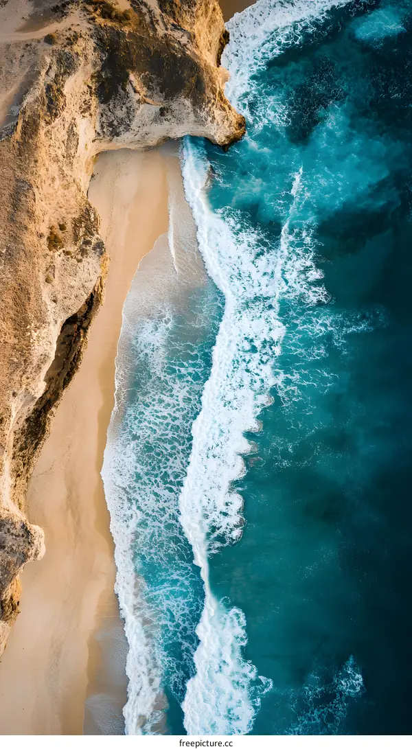 Aerial View of Waves Crashing on Sandy Beach with Cliff