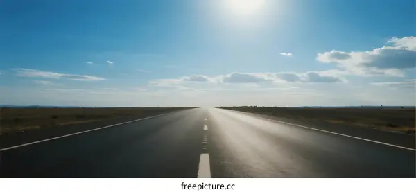 Sunlit open road stretching under clear blue sky