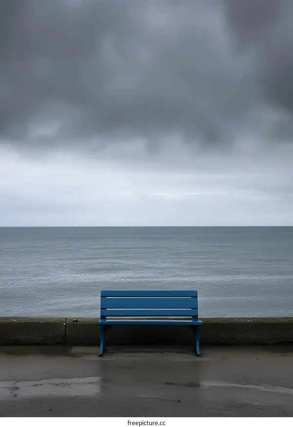 Blue Bench on a Concrete Wall Overlooking the Ocean Under a Cloudy Sky