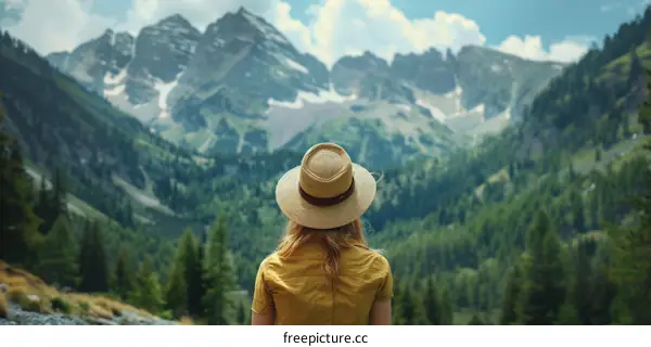 woman in yellow shirt and straw hat looking at mountain range