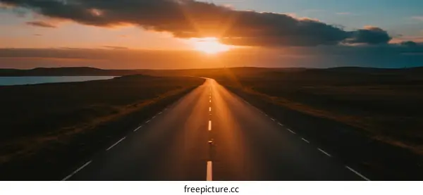 The sun setting over a long empty road with scenic view