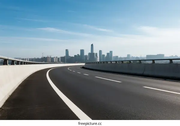 Smooth highway with city skyline in the background under clear blue sky