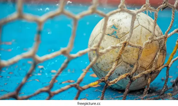 An old soccer ball in a goal net