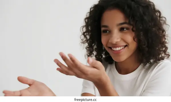 Young woman with curly hair and open hands smiling happily