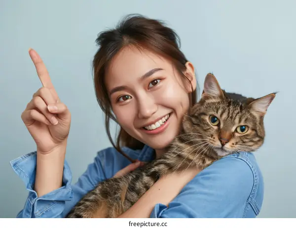 A young Asian woman is smiling and hugging a cat