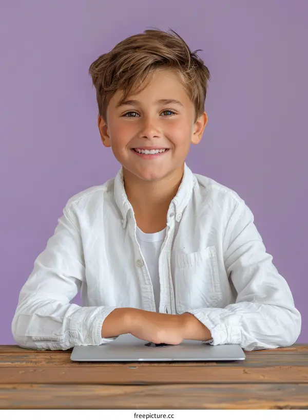 Portrait of a smiling boy sitting at a table with a laptop