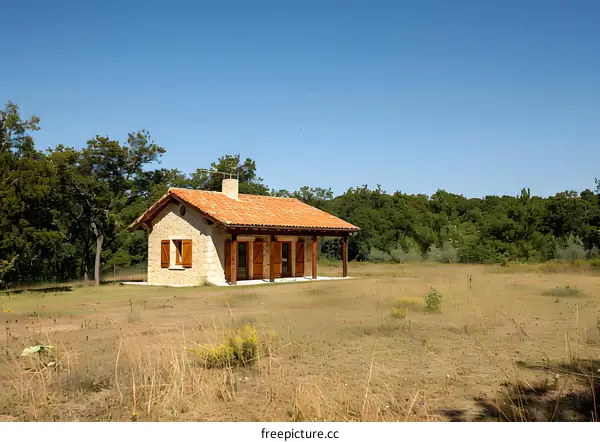 Small stone house in the middle of a dry grass field