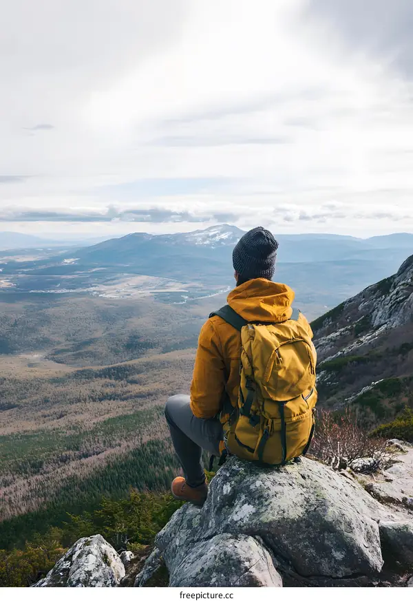 Man Sitting on Mountain Top with Backpack Looking at View