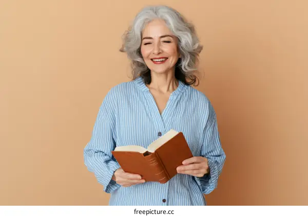 Senior woman reading a book against a beige background