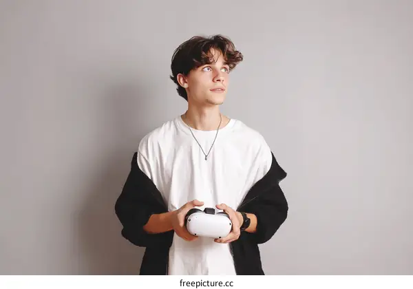 Young man holding VR controller against gray background