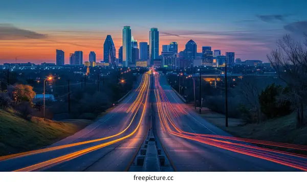 A long exposure photo of a highway at night with the Dallas skyline in the background