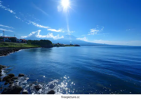 Sunlit Seaside Town with Majestic Mountain View