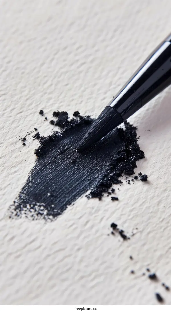 Black Eyeshadow Scattered on White Surface with Makeup Brush