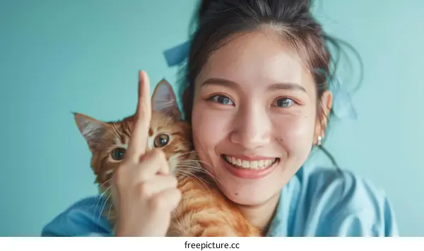 A young woman is smiling and holding a cat.