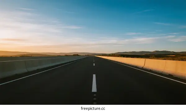 Empty road under clear blue sky during sunrise or sunset