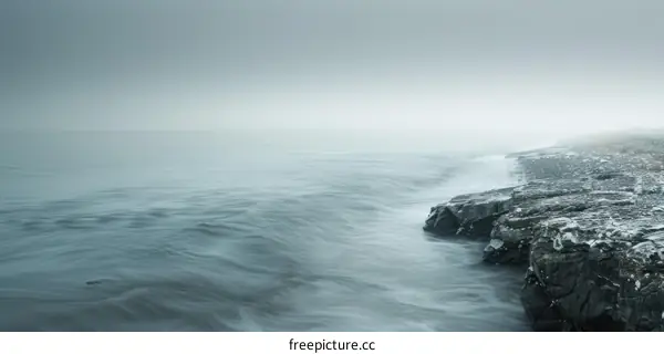 Black and white photo of a rocky coast with waves crashing against it