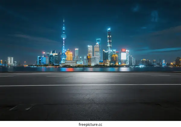 Night view of modern city skyline with empty road in foreground