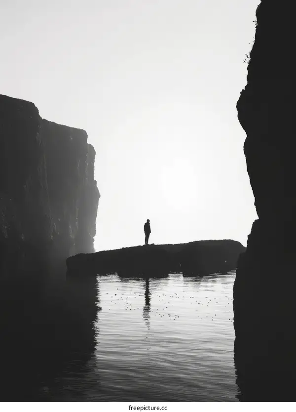 Man standing alone on rock in middle of ocean