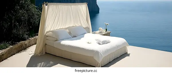 White Bed with Canopy on Clifftop Overlooking Ocean