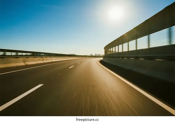 Sunlit highway with clear blue sky and smooth road surface
