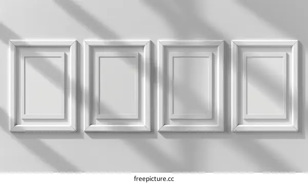 Four white frames on a white concrete wall with soft shadows