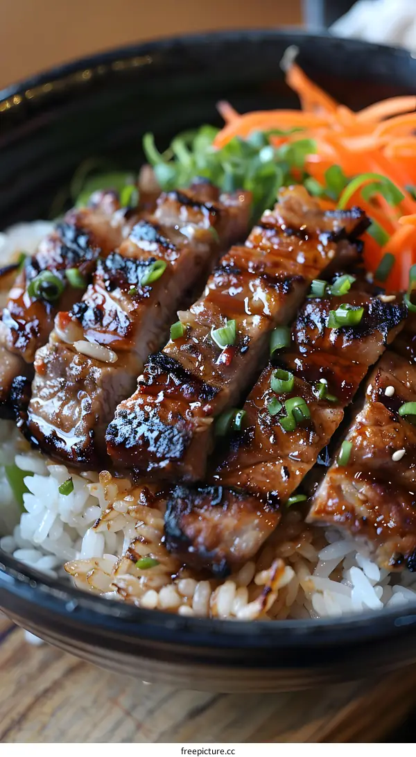 A bowl of rice topped with grilled pork and vegetables