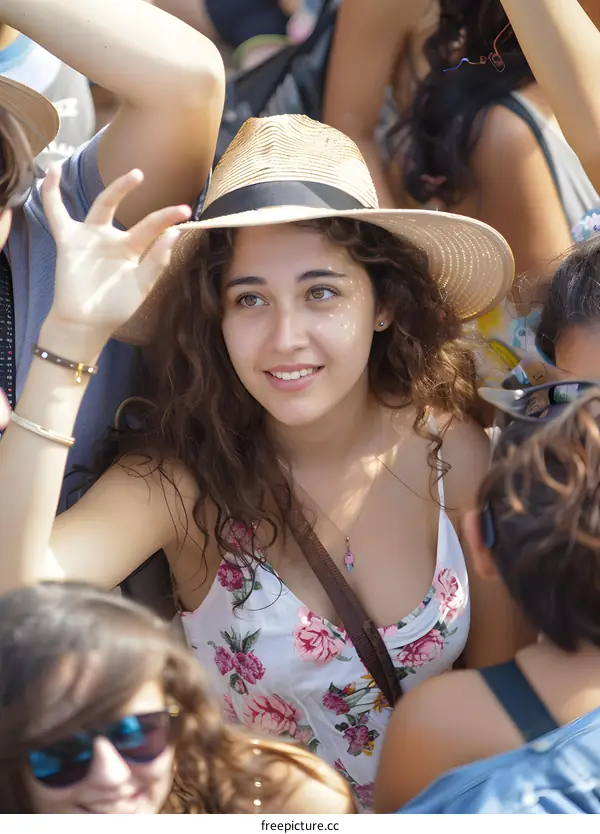Young Woman with Curly Hair Wearing a Straw Hat and Floral Dress in a Crowd