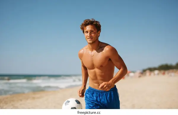 Young Man Playing Football on the Beach