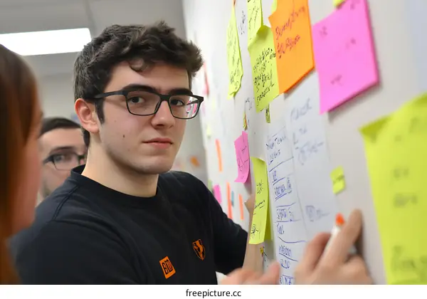 Young Man Writing on Whiteboard with Sticky Notes